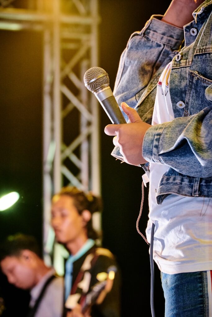 man in blue denim jacket holding microphone
