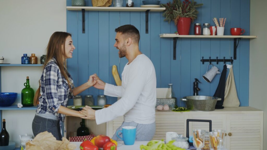 Cheerful and attractive young couple in love dancing together latin dance in the kitchen at home
