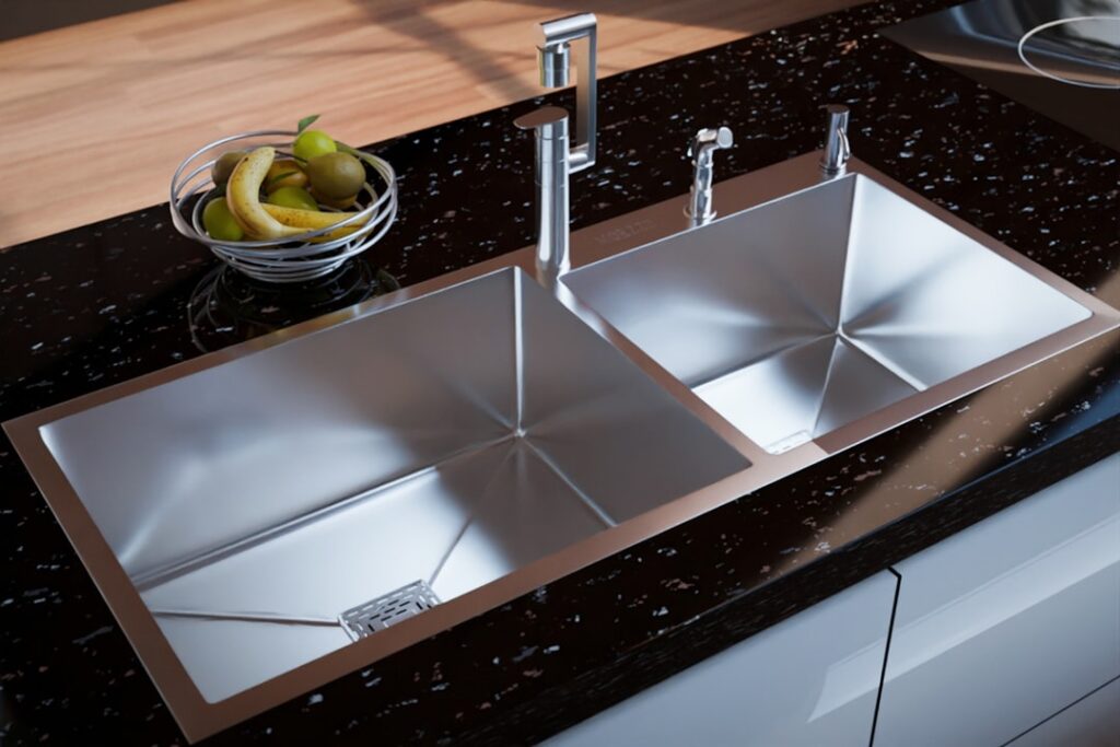 A premium double-bowl stainless steel kitchen sink installed in a sleek black stone countertop, complemented by a modern chrome faucet. The geometric basin design enhances functionality and water flow, while the polished finish adds a refined, contemporary touch. Natural wood accents and minimal décor elements complete the look, making it ideal for luxury modular kitchens and modern home interiors.