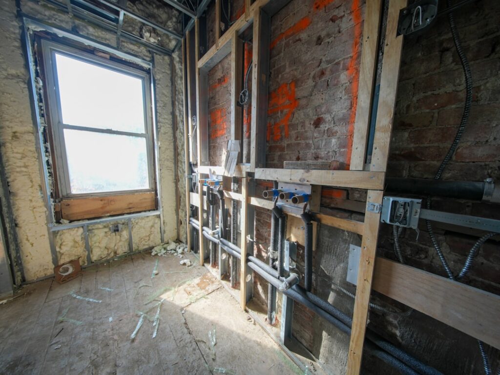A three-story brownstone stands in mid-transformation, captured at the raw and honest “before” stage of a full interior renovation. These images document a moment that usually disappears once the walls are closed and the finishes are installed — exposed framing, stripped ceilings, rough staircases, and open corridors that reveal the building’s original structure and hidden history. Light spills in through skylights and tall windows, cutting through layers of dust and unfinished surfaces, creating a quiet contrast between decay and renewal. The space feels both industrial and intimate: narrow